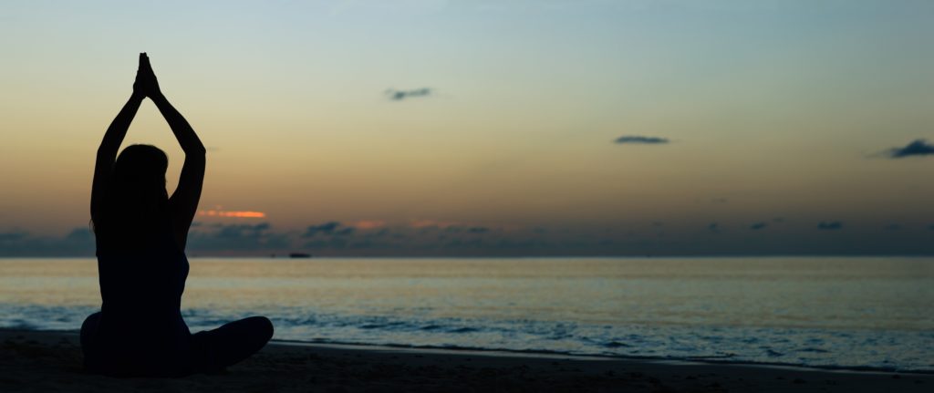 woman in our holistic mental health program in Florida practices yoga on the beach 
